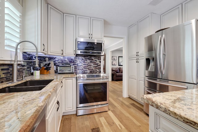 6206 Bayou Blvd, Baytown, TX 77521 - kitchen with stainless steel appliances, a sink, tasteful backsplash, and white cabinets
