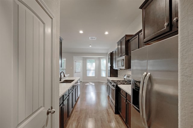 9533 E Woodmark, Conroe, TX 77304 - kitchen with stainless steel appliances, a sink, light wood-style flooring, dark brown cabinets, and recessed lighting
