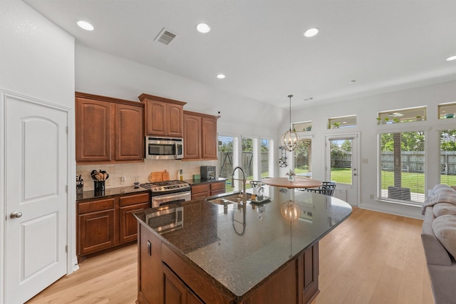 28803 Crested Butte Dr, Katy, TX 77494 - kitchen with stainless steel appliances, a sink, an island with sink, light wood-style floors, and tasteful backsplash
