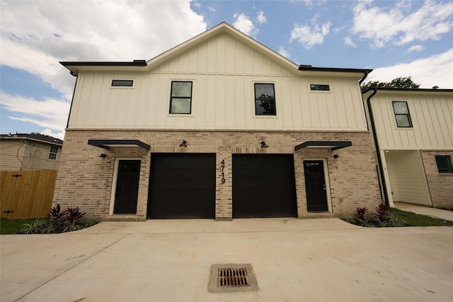 modern farmhouse style home featuring brick siding, concrete driveway, board and batten siding, an attached garage, and fence