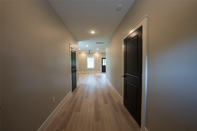 hall featuring light wood-style flooring, baseboards, and recessed lighting