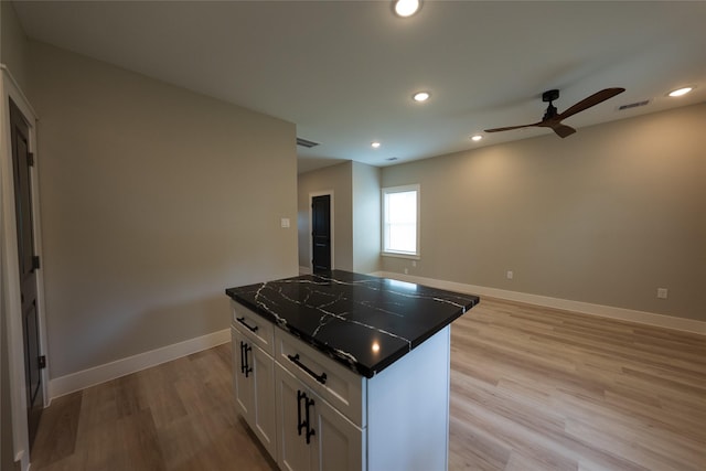 kitchen with a center island, ceiling fan, white cabinets, light wood-style floors, and baseboards