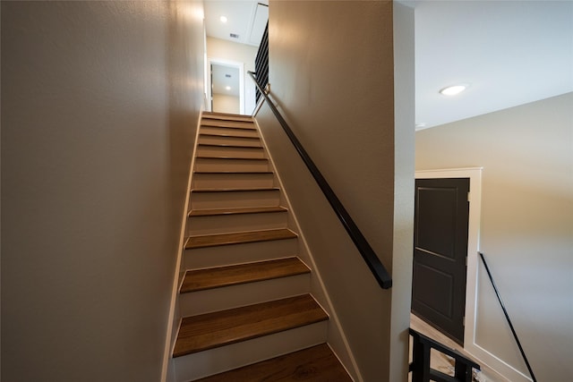 stairway featuring wood finished floors and recessed lighting