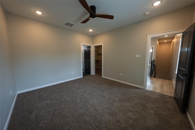 unfurnished bedroom featuring carpet floors, a spacious closet, baseboards, recessed lighting, and a ceiling fan