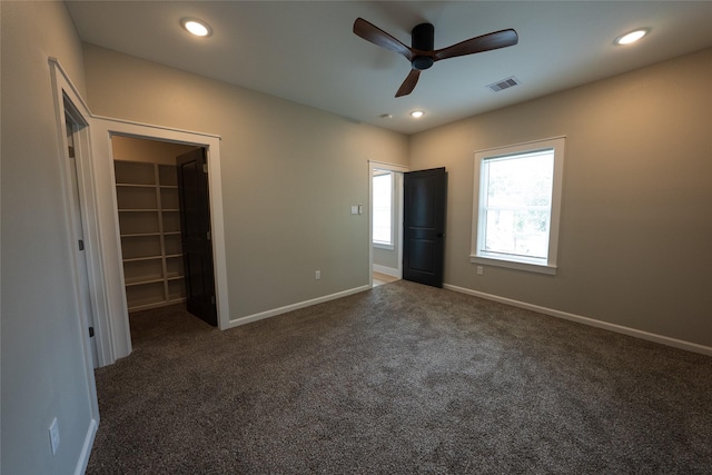 unfurnished bedroom with carpet floors, a walk in closet, baseboards, recessed lighting, and ceiling fan