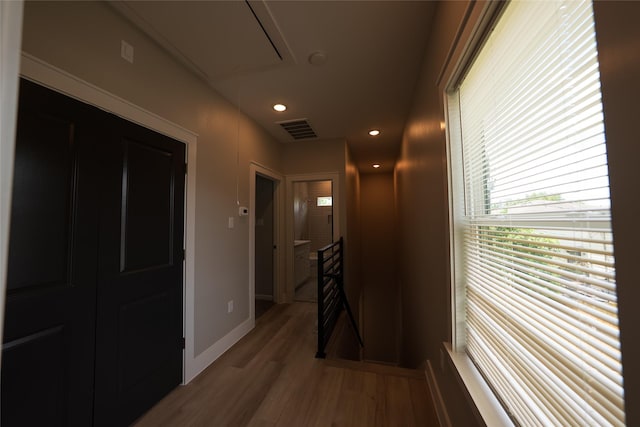 hall featuring an upstairs landing, attic access, wood finished floors, healthy amount of natural light, and recessed lighting