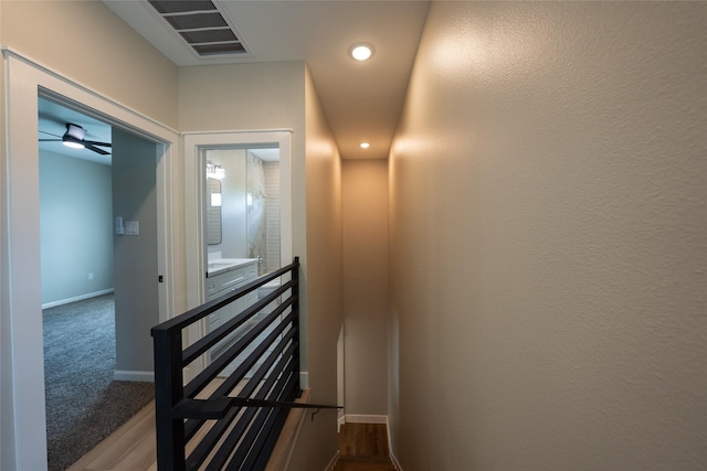 hall with an upstairs landing, baseboards, and recessed lighting