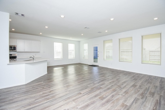7303 Dover View Ln, Katy, TX 77493 - unfurnished living room with recessed lighting, light wood finished floors, baseboards, and a sink