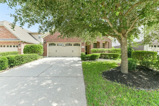 27 Canterborough Pl, Tomball, TX 77375 - view of front of property featuring brick siding, a garage, and concrete driveway