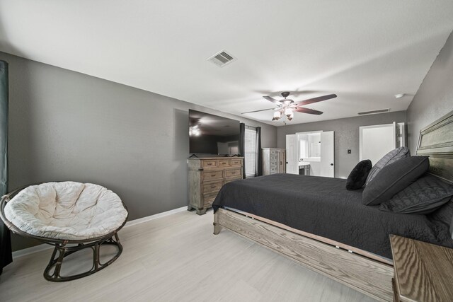 bedroom with light wood-style floors, baseboards, ceiling fan, and ensuite bath
