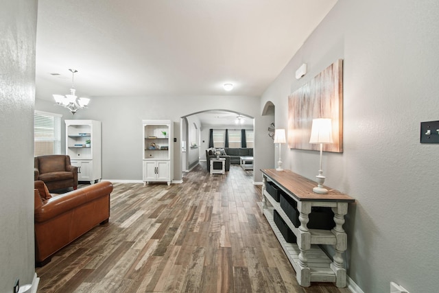 living room with arched walkways, plenty of natural light, wood finished floors, and baseboards