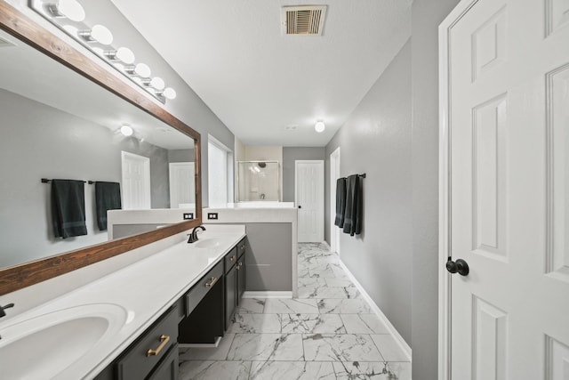 full bathroom with marble finish flooring, a stall shower, baseboards, and double vanity