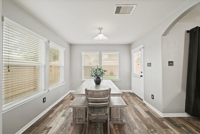 dining room with arched walkways, dark wood finished floors, and baseboards