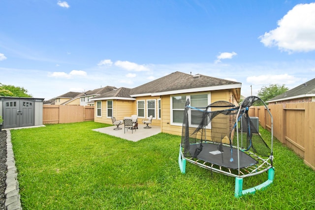 back of house with a trampoline, a patio, a storage unit, an outbuilding, and cooling unit