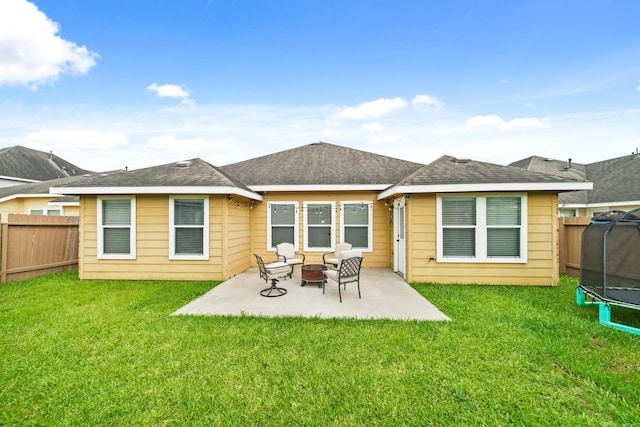 rear view of property featuring a trampoline, a patio area, and an outdoor fire pit