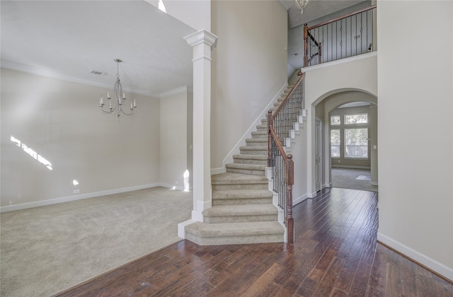 foyer featuring arched walkways, stairs, baseboards, wood finished floors, and ornamental molding