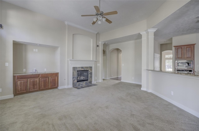 unfurnished living room featuring ceiling fan, a tiled fireplace, carpet floors, and baseboards