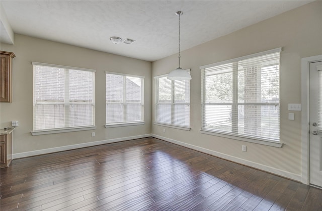 unfurnished dining area featuring baseboards, plenty of natural light, and dark wood-type flooring
