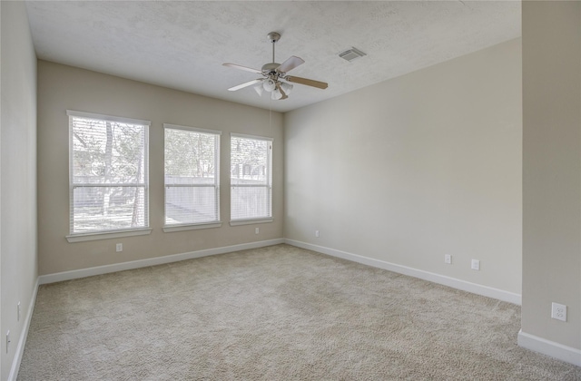 carpeted empty room with healthy amount of natural light, ceiling fan, baseboards, and a textured ceiling