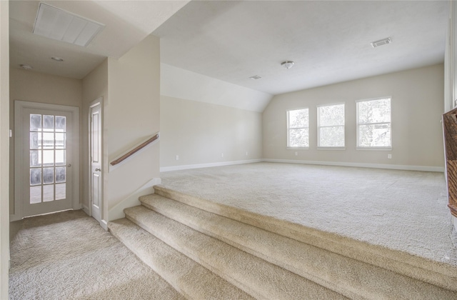 unfurnished living room featuring carpet, baseboards, stairway, and lofted ceiling