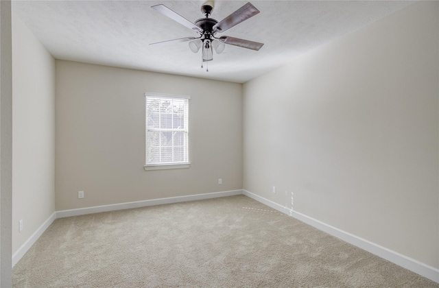 carpeted spare room with baseboards and a ceiling fan