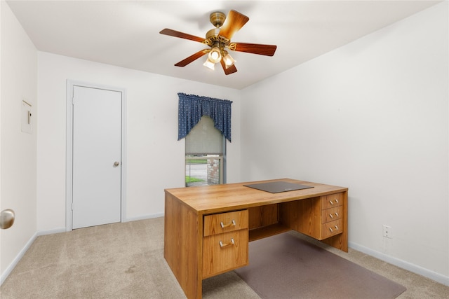 unfurnished office with light colored carpet, a ceiling fan, and baseboards