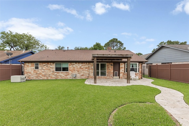 rear view of house with a patio area, roof with shingles, brick siding, and a chimney
