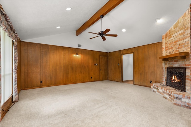 unfurnished living room featuring a brick fireplace, light colored carpet, a ceiling fan, and wooden walls