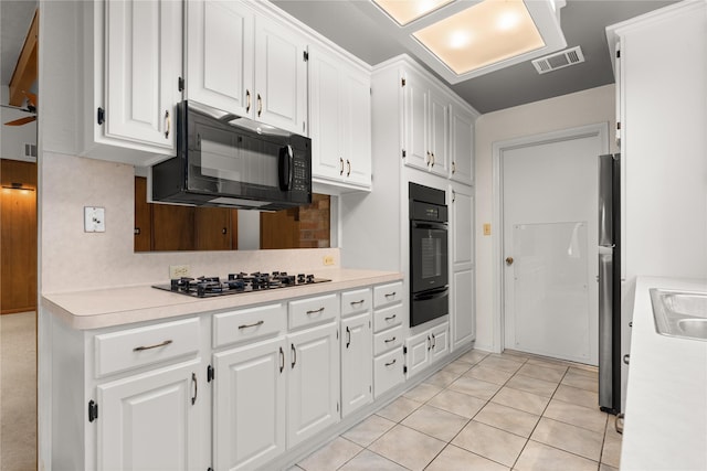 kitchen with black appliances, a warming drawer, white cabinetry, backsplash, and light countertops