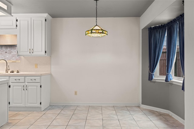 kitchen featuring white cabinetry, light countertops, pendant lighting, baseboards, and tasteful backsplash