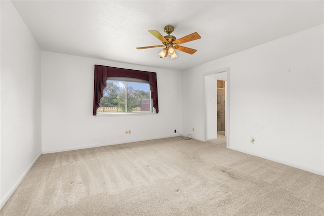 carpeted empty room featuring a ceiling fan and baseboards