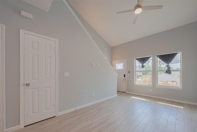 spare room with ceiling fan, baseboards, light wood-style floors, and vaulted ceiling