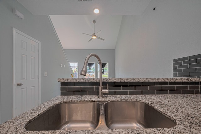 kitchen view of a sink, stone countertops, and decorative backsplash