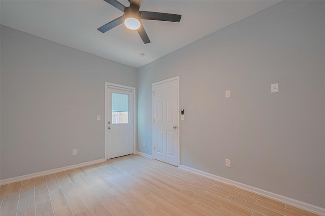 unfurnished room with a ceiling fan, baseboards, and light wood-style flooring