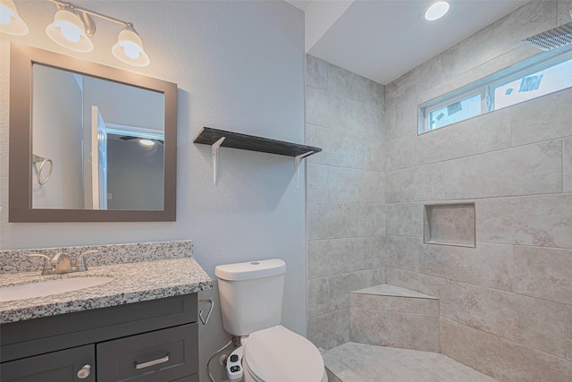 full bath with vanity, toilet, and a tile shower