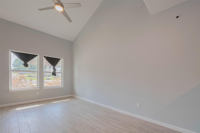 spare room featuring lofted ceiling, ceiling fan, light wood-type flooring, and baseboards