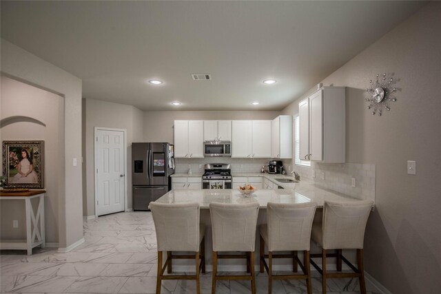 14707 Fairy Tern Ln, Houston, TX 77049 - kitchen with stainless steel appliances, a peninsula, a sink, light marble finish floors, and a kitchen bar