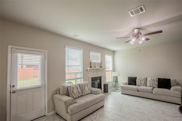 14707 Fairy Tern Ln, Houston, TX 77049 - living area featuring light marble finish floors, ceiling fan, and a glass covered fireplace
