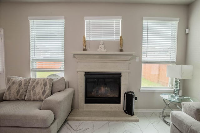 14707 Fairy Tern Ln, Houston, TX 77049 - living area with marble look tile flooring, a glass covered fireplace, and baseboards