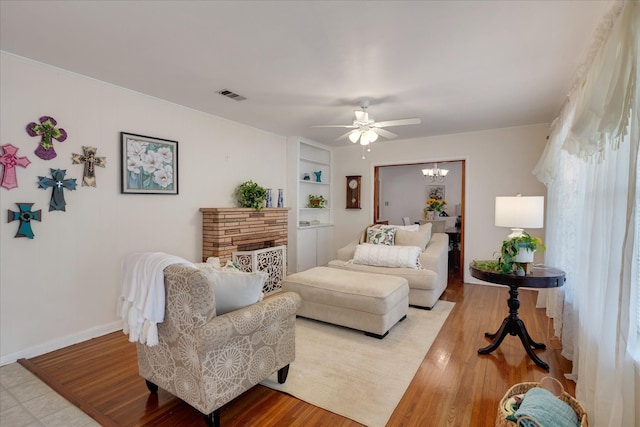 111 Circle Dr, Cleveland, TX 77327 - living room featuring a ceiling fan, built in shelves, light wood-type flooring, and a chandelier