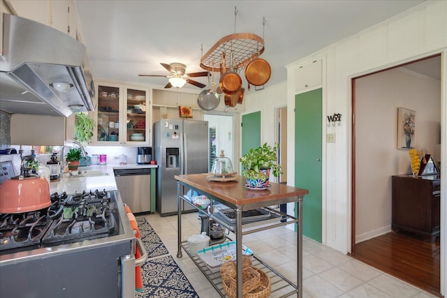 111 Circle Dr, Cleveland, TX 77327 - kitchen featuring stainless steel appliances, exhaust hood, light countertops, ceiling fan, and glass insert cabinets