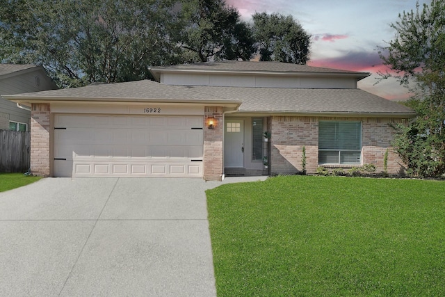 view of front facade with an attached garage, brick siding, driveway, and a front lawn