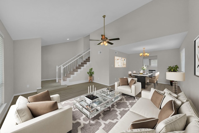 living area with stairway, a chandelier, wood finished floors, ceiling fan, and baseboards