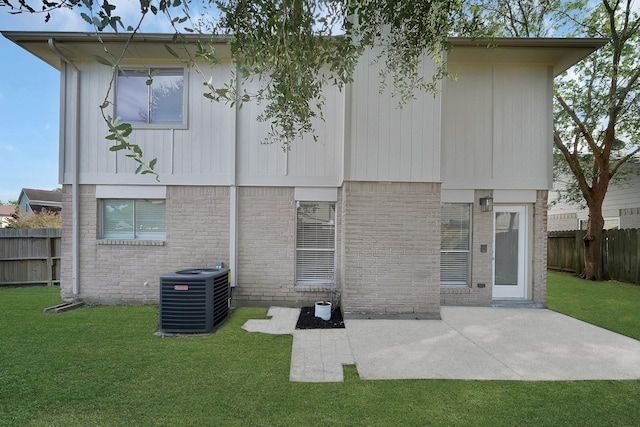 rear view of house featuring central AC unit, brick siding, and a patio