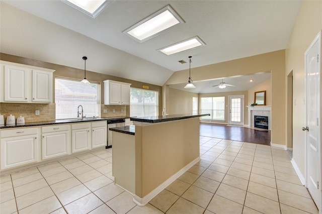 1826 Oak Lodge Dr, Pearland, TX 77581 - kitchen with stainless steel dishwasher, vaulted ceiling, light tile patterned floors, decorative backsplash, and a tiled fireplace