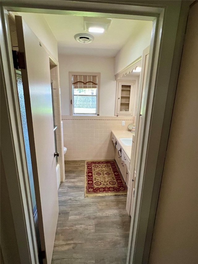 205 Cathy Dr, Hallettsville, TX 77964 - bathroom featuring tile walls, vanity, toilet, wood finished floors, and a wainscoted wall