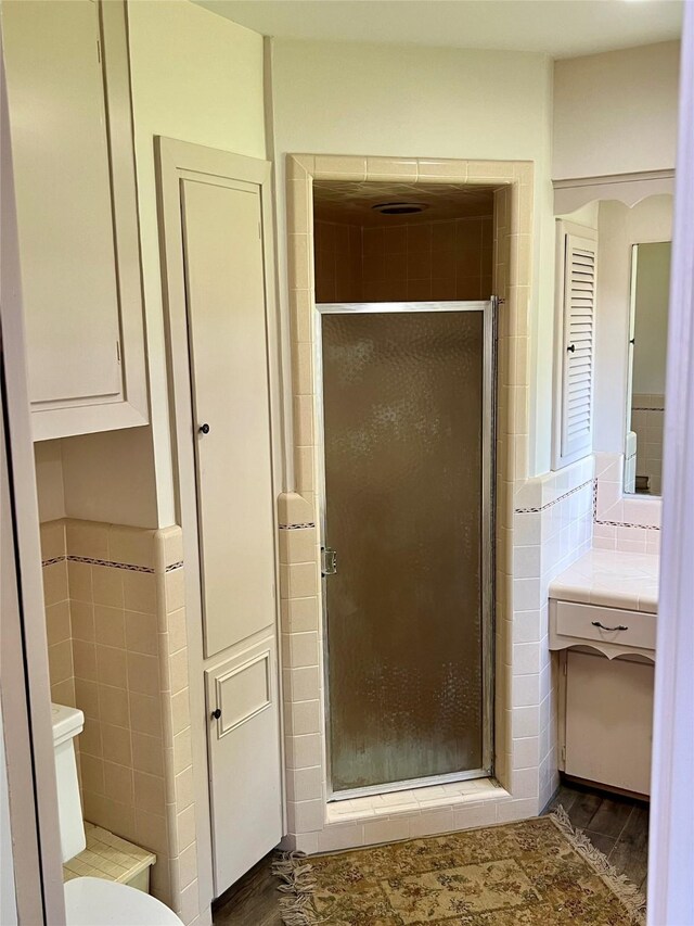 205 Cathy Dr, Hallettsville, TX 77964 - full bathroom with tile walls, wood finished floors, a stall shower, vanity, and toilet