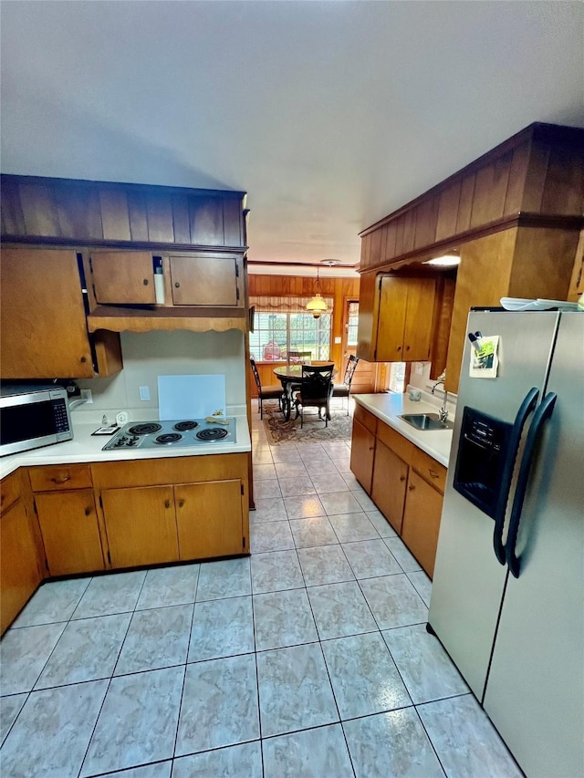 205 Cathy Dr, Hallettsville, TX 77964 - kitchen featuring appliances with stainless steel finishes, light countertops, a sink, light tile patterned floors, and wooden walls