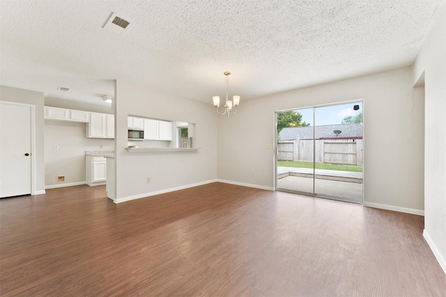 12215 Oldenburg Ln, Houston, TX 77065 - unfurnished living room with a chandelier, a textured ceiling, dark wood-style flooring, and baseboards