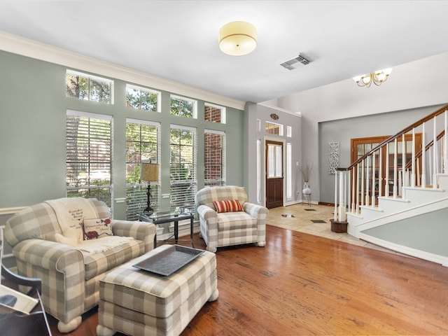 living area featuring stairway, a chandelier, and wood finished floors
